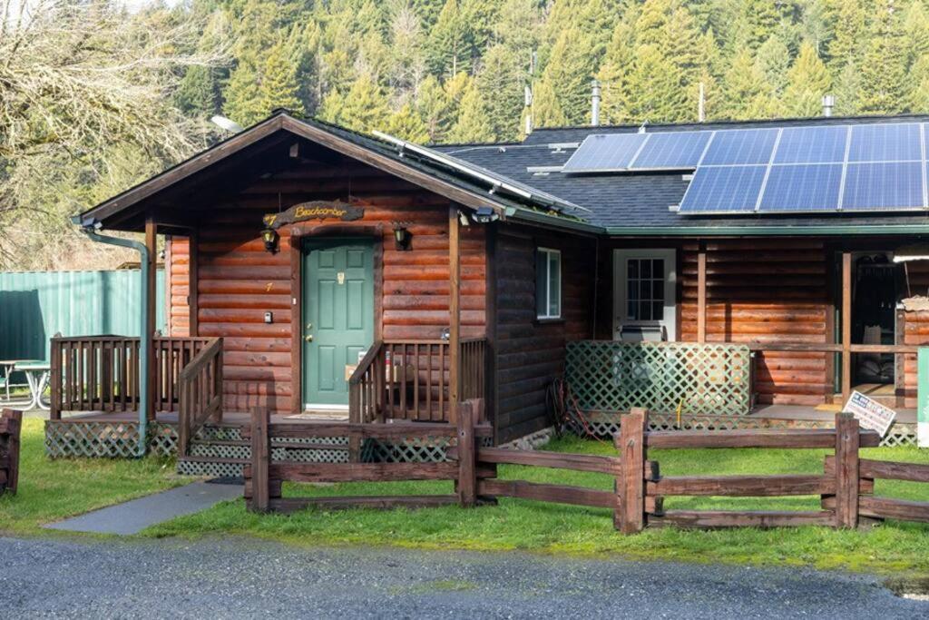 Cabaña de madera con puerta verde y paneles solares en Elk Meadow Cabins 7 Beachcomber Studio, en Orick