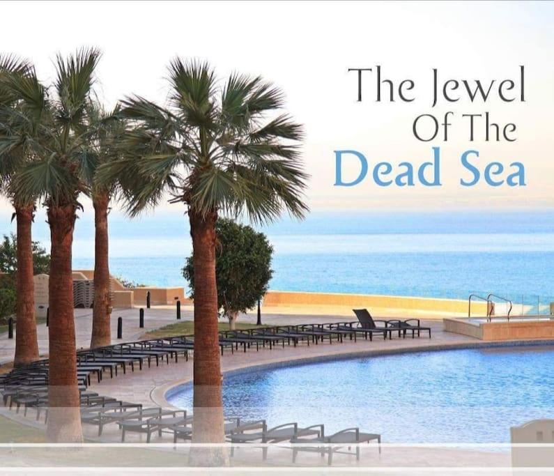una piscina con palmeras junto a una playa en Dead Sea Jordan Sea View Samarah Resort Traveler Award 2024 winner en Sowayma