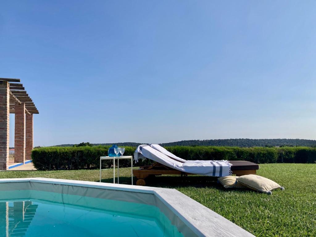 una piscina con una mesa y un banco junto a ella en Herdade da Burquilheira, en Alcáçovas