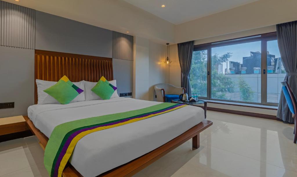 a bedroom with a large bed and a large window at Treebo Trend Regency - Bund Garden, Dhole Patil Road in Pune
