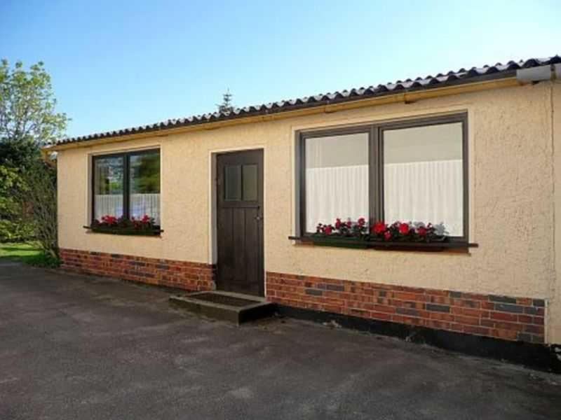 a house with two windows and a door with red flowers at Ruegen_Fewo 102 in Sagard