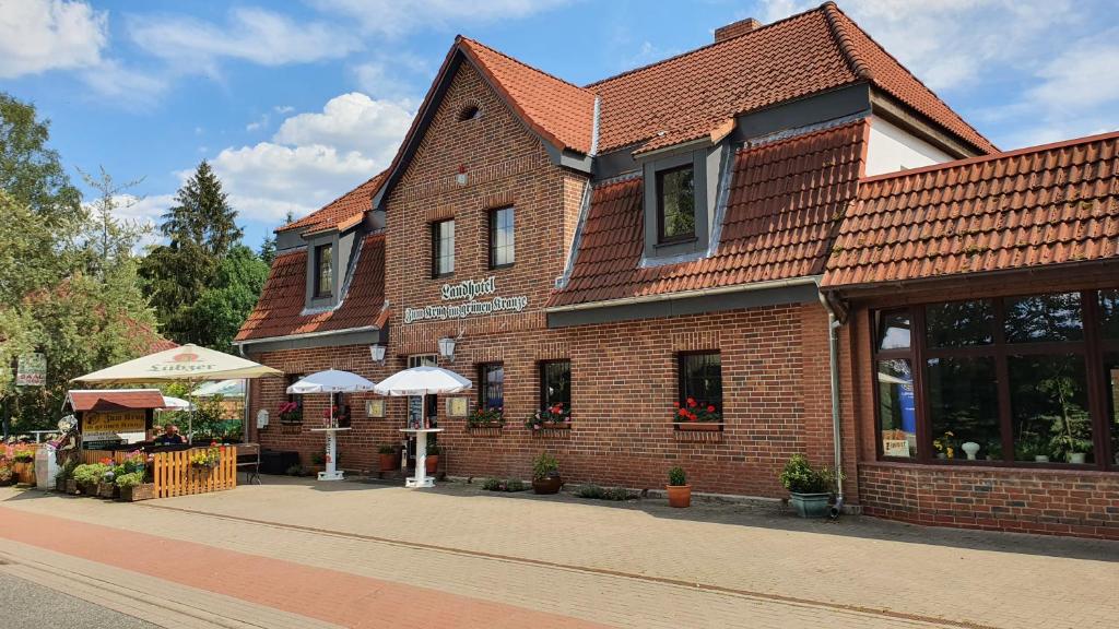 ein Backsteingebäude mit Sonnenschirmen davor in der Unterkunft Gästezimmer-Zum Krug im grünen Kranze in Pätower Steegen