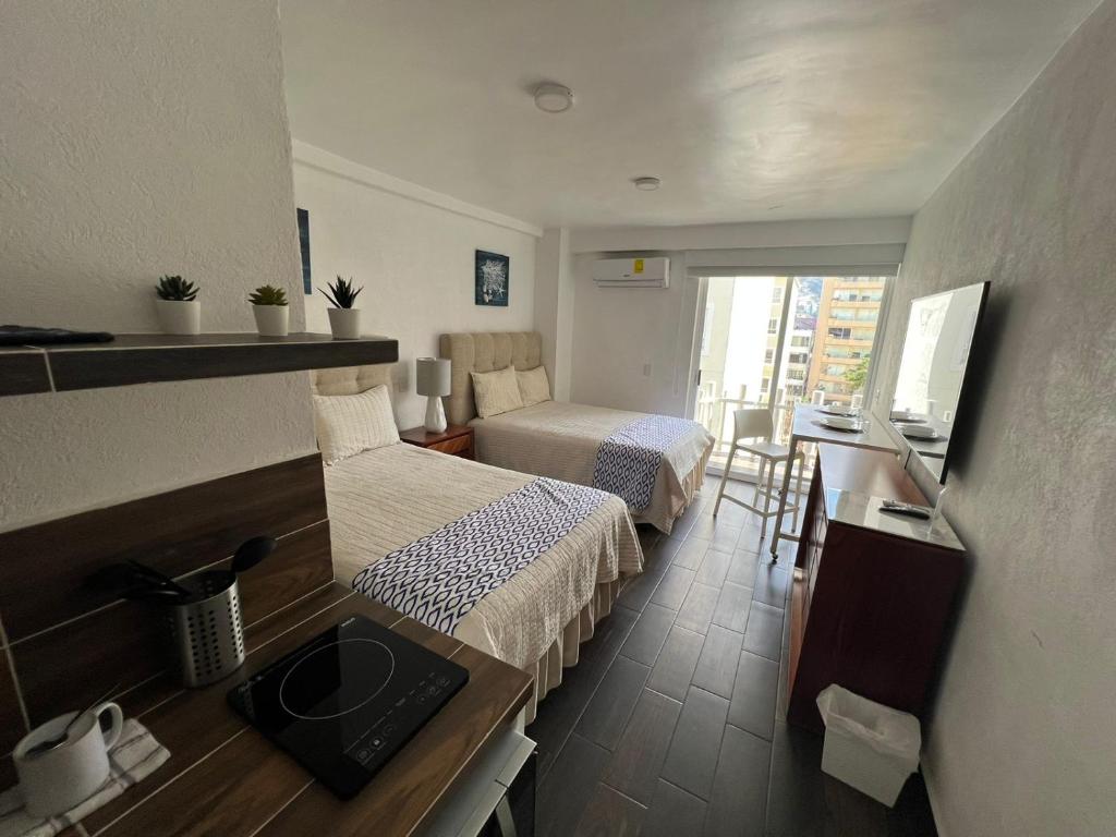 um pequeno quarto de hotel com duas camas e uma cozinha em SKY INN Acapulco Y condominio mediterrane em Acapulco