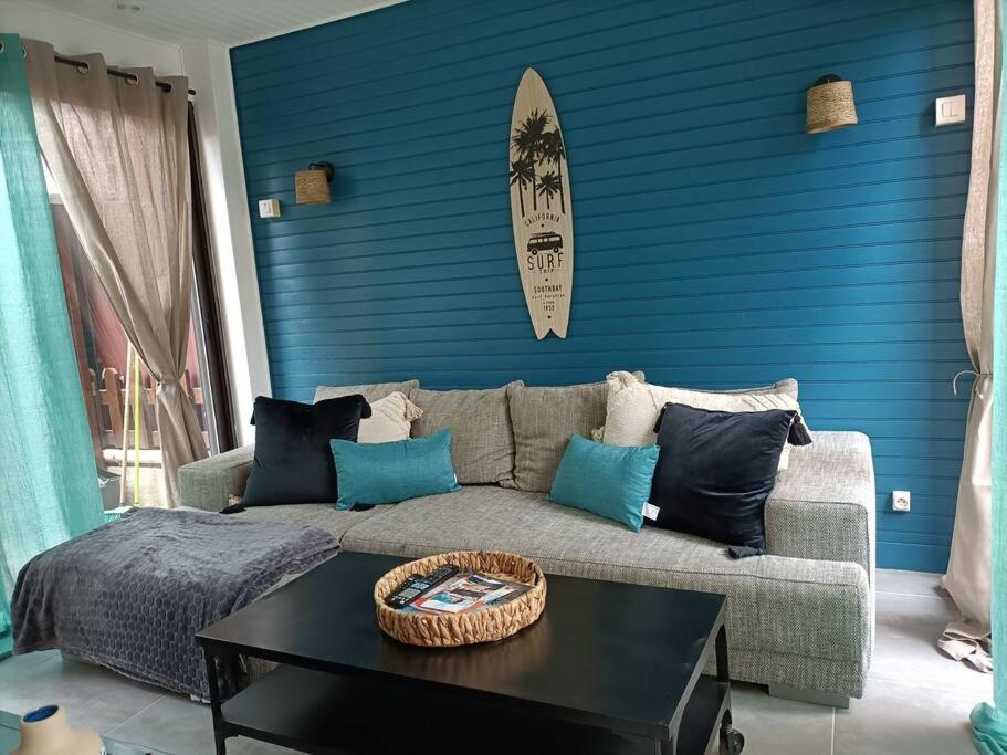 ein Wohnzimmer mit einem Sofa und einem Surfbrett auf einer blauen Wand in der Unterkunft Le Sept in Gruissan