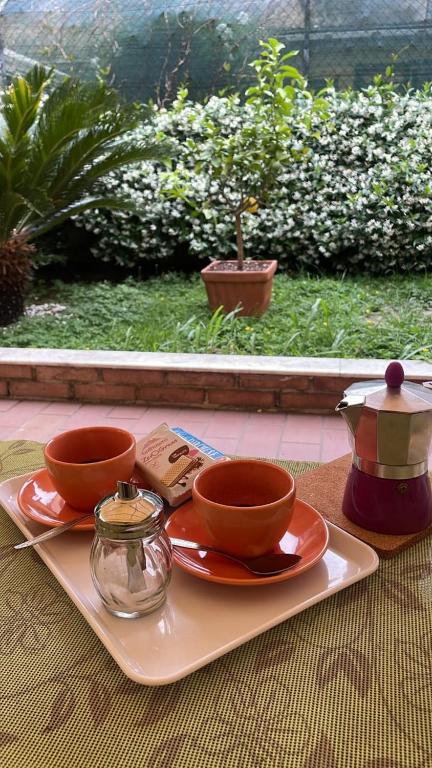 a tray with two cups and plates on a table at Bilocale Carrara Centro con giardino e parcheggio moto in Carrara