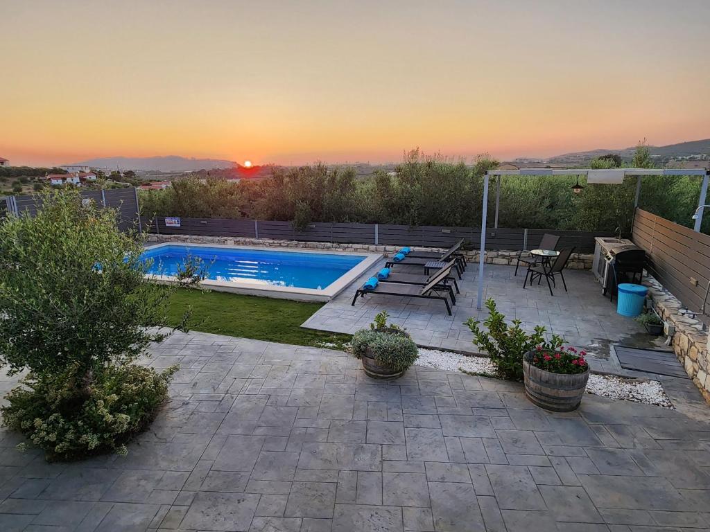 a backyard with a swimming pool and a sunset at Villa Sheila with private pool in Roumelí