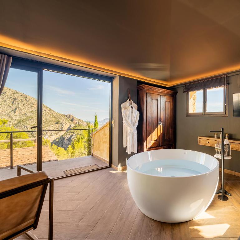 a bathroom with a large tub and a large window at Boutique Hotel Finca el Tossal - Adults Only in Bolulla