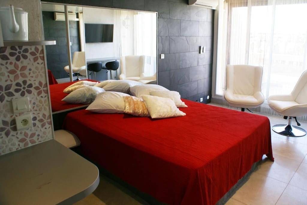 - une chambre avec 2 lits et une couverture rouge dans l'établissement Studio 309, Héliopolis AB, village naturiste, au Cap d'Agde