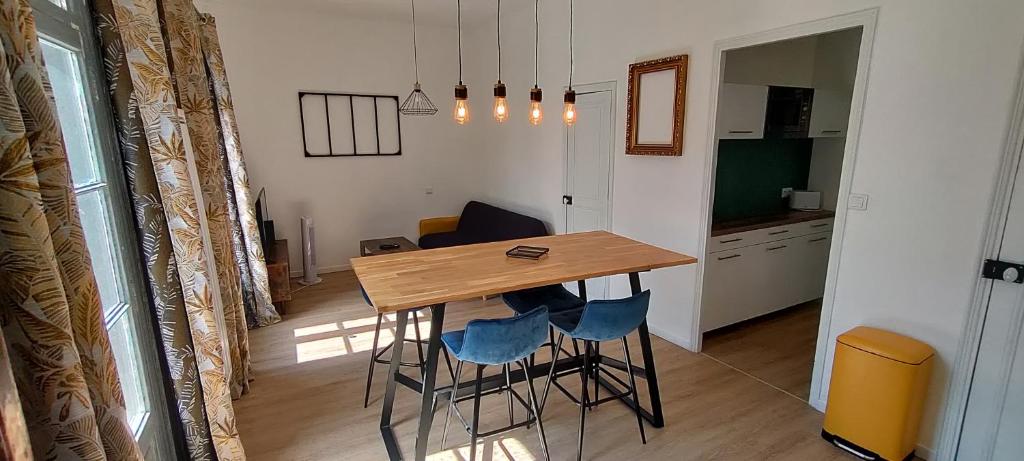 une cuisine avec une table en bois et des chaises bleues dans l'établissement Appartement ensoleillé, à Perpignan
