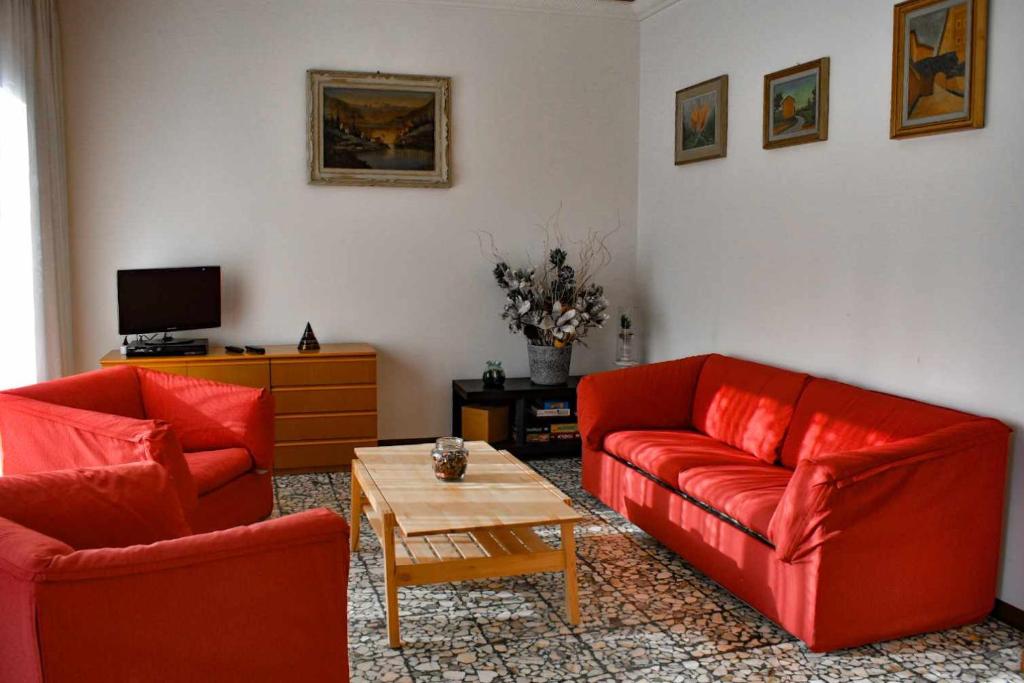 Ciceri Properties Montebello في فيربانيا: غرفة معيشة بها كنبتين حمراء وطاولة قهوة