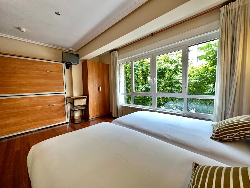 a bedroom with a large bed and a large window at Pension Anoeta in San Sebastián