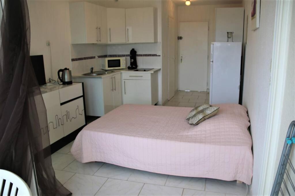 een kleine keuken met een bed en een koelkast bij Studio 82, Héliopolis FGH au Village naturiste in Cap d'Agde