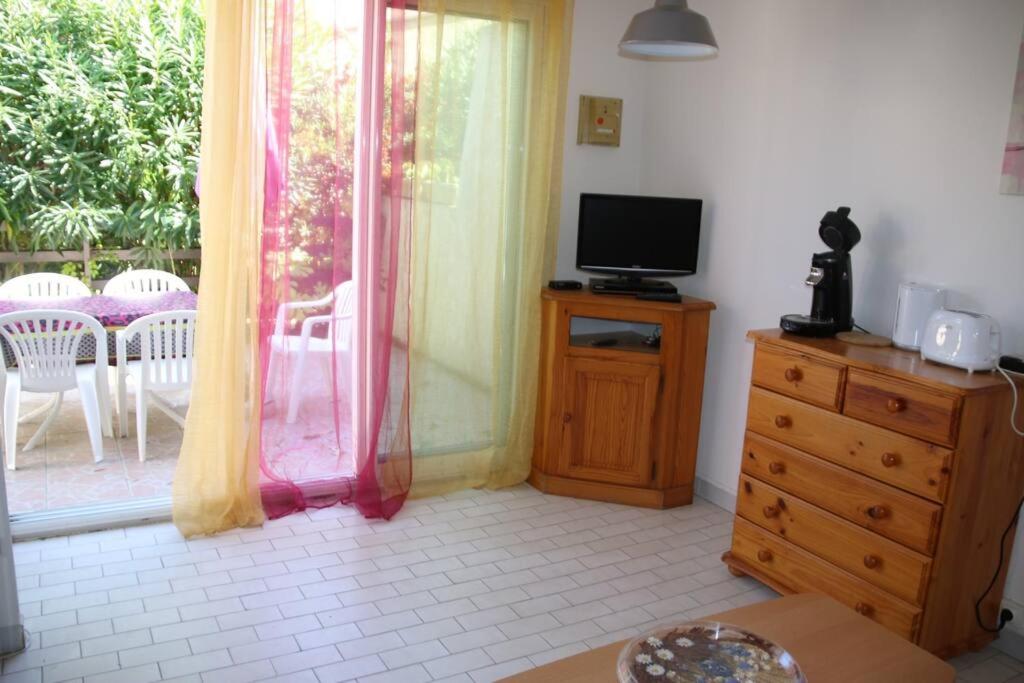 un salon avec une télévision sur une commode et une fenêtre dans l'établissement Villa 24, Port Vénus au village naturiste, au Cap d'Agde