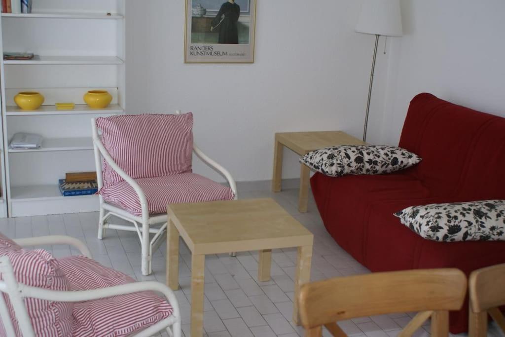 een woonkamer met een rode bank en stoelen bij Appart 801, Tennis village in Cap d'Agde