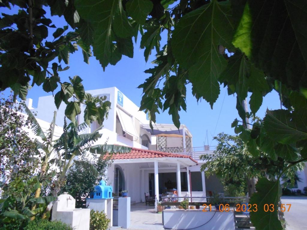 Una casa blanca con un árbol delante. en Garifalia Studios, en Kalamaki