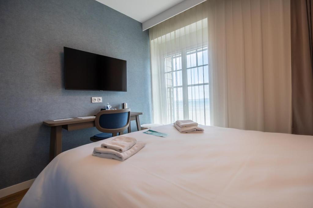 a bedroom with a bed with a desk and a television at Hôtel de la Baie in Crozon