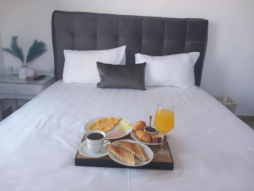a tray of food and a glass of orange juice and breakfast on a bed at Panorama in Methana