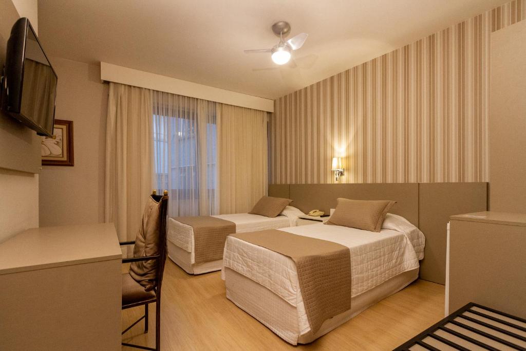 a hotel room with two beds and a television at Curitiba Palace Hotel in Curitiba
