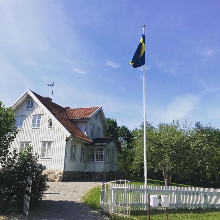 a flag flying in front of a white house at Rum på hästgård in Holmsjö