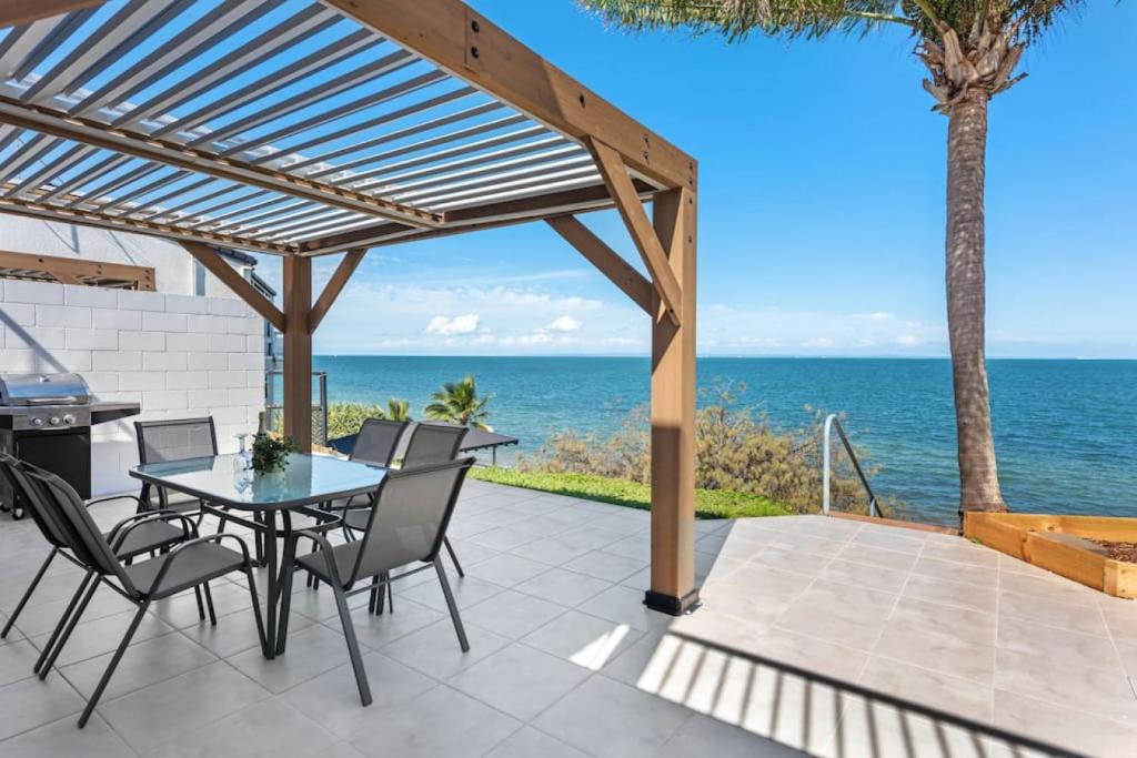 a patio with a table and chairs and the ocean at Sunrise Two Bedroom Apartment in Redcliffe