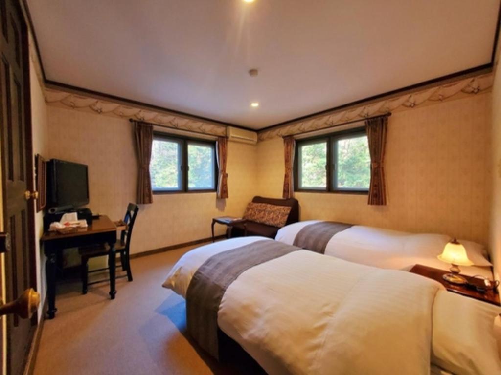 富士河口湖町にあるGusthof Lumiere - Vacation STAY 41349vのベッド2台、デスク、テレビが備わるホテルルームです。