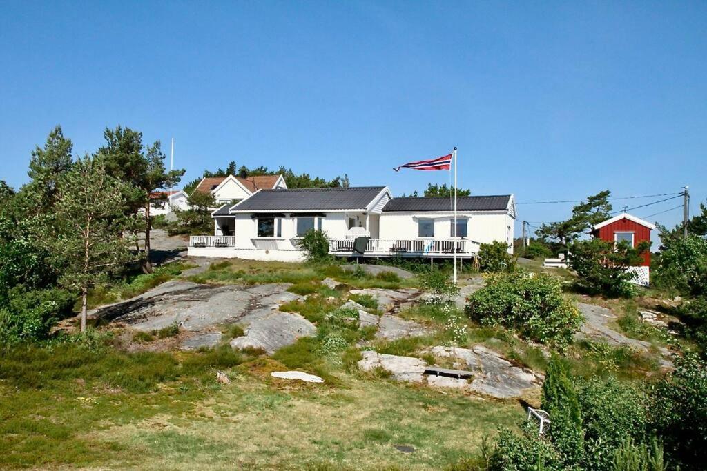 a house on top of a hill with a flag at Southern cottage with terrace and magnificent view in Lillesand