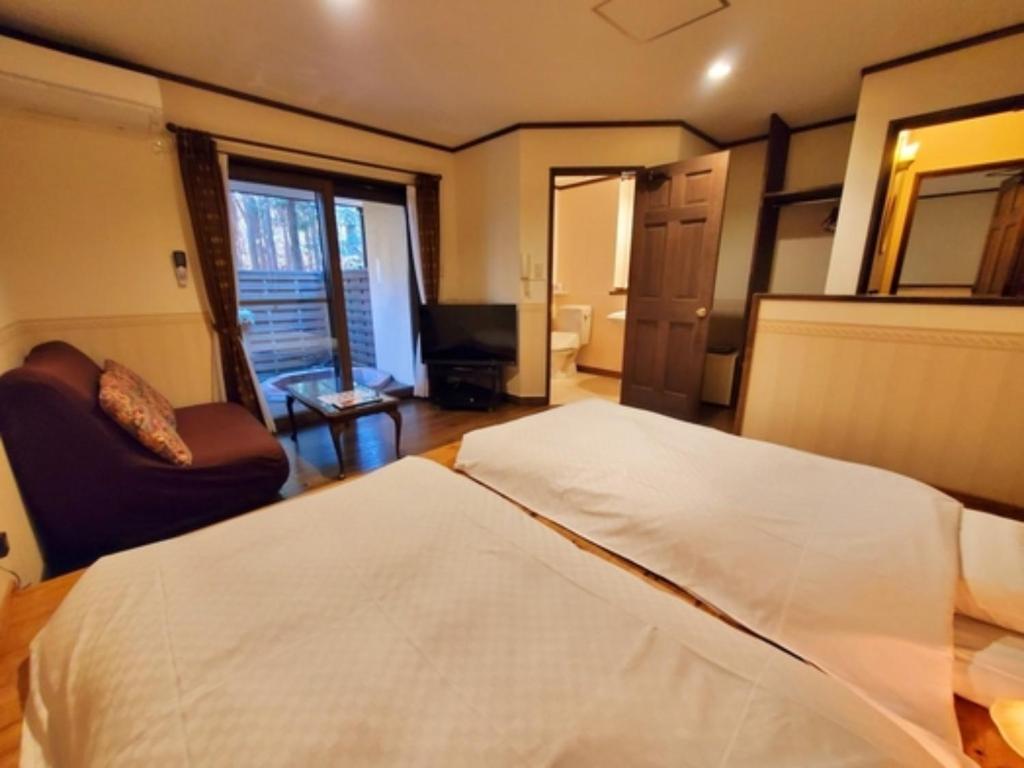 een slaapkamer met een bed, een bank en een televisie bij Gusthof Lumiere - Vacation STAY 41339v in Fujikawaguchiko