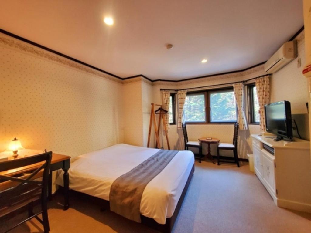 a hotel room with a bed and a television at Gusthof Lumiere - Vacation STAY 41353v in Fujikawaguchiko