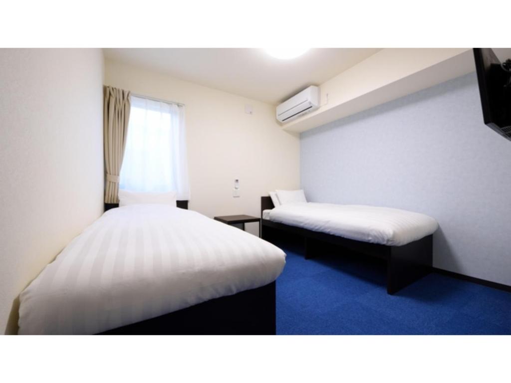 気仙沼市にあるLa'gent Inn Kesennuma - Vacation STAY 85809vのベッド2台と窓が備わる小さな客室です。