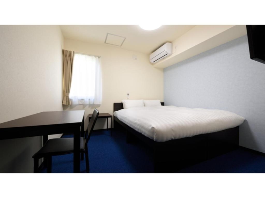 a small room with a bed and a desk and a table at La'gent Inn Kesennuma - Vacation STAY 85808v in Kesennuma