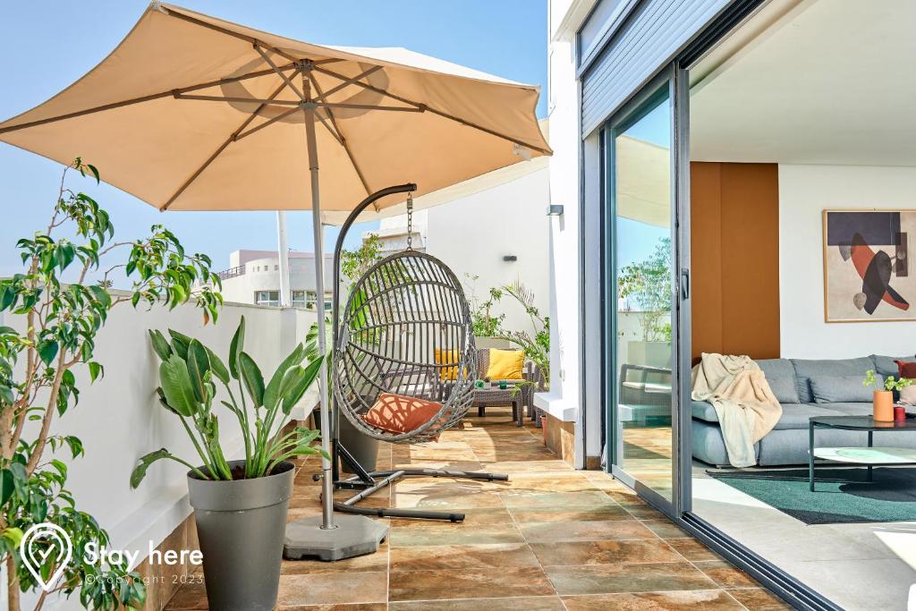 une terrasse avec une balançoire et un parasol dans l'établissement Stayhere Rabat - Agdal 3 - Prestige Residence, à Rabat