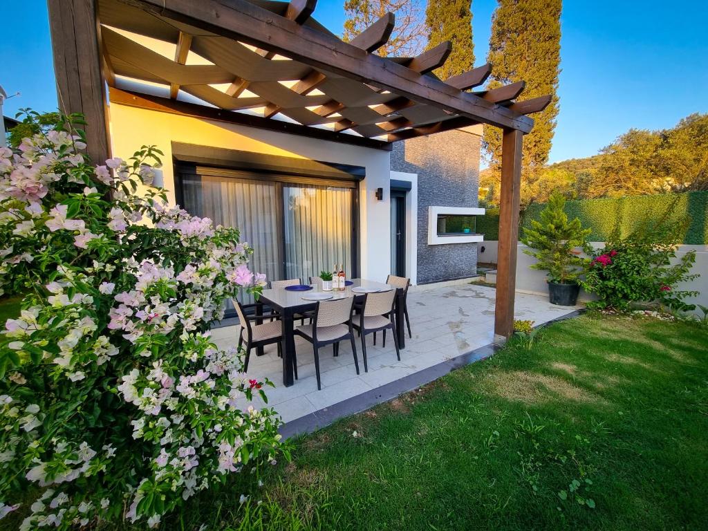 patio con tavolo e sedie sotto un pergolato in legno di Suelo Flat Villa for Family a Turgutreis