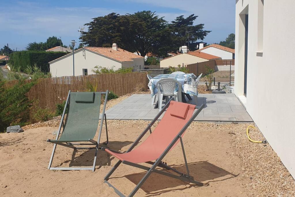 two chairs and a table on a patio at La Perséide - Maison neuve 900 m plage in Notre-Dame-de-Monts