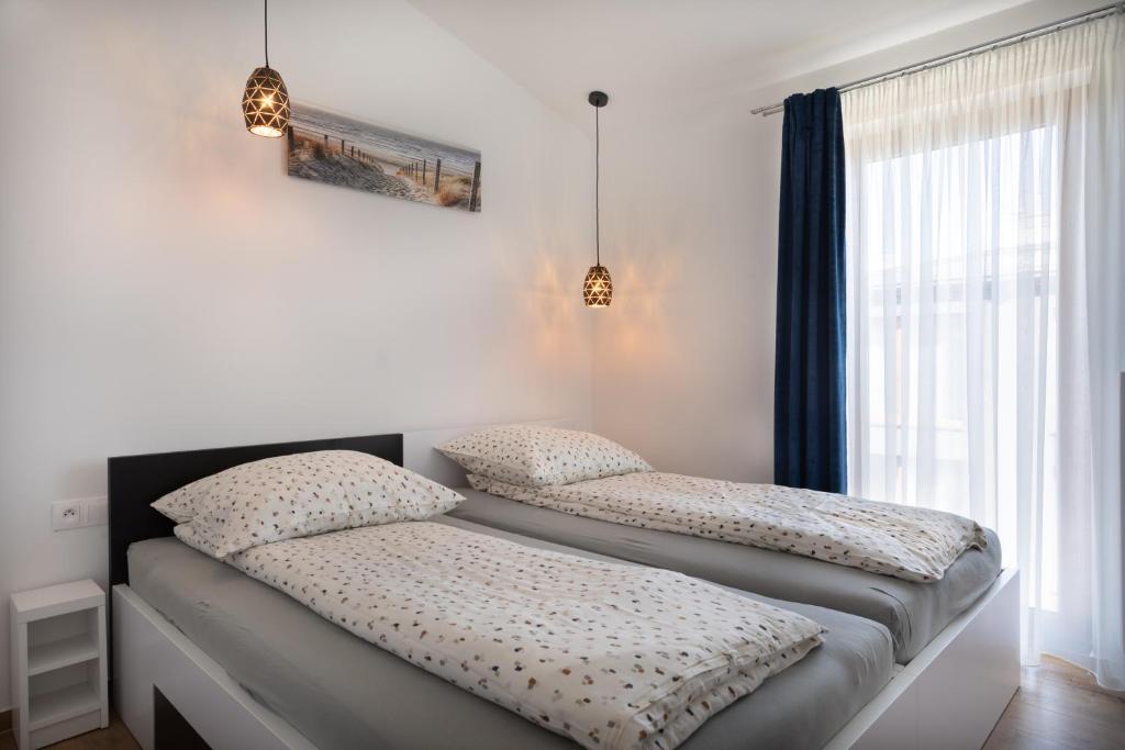 two twin beds in a room with a window at Morski Apartament in Sarbinowo