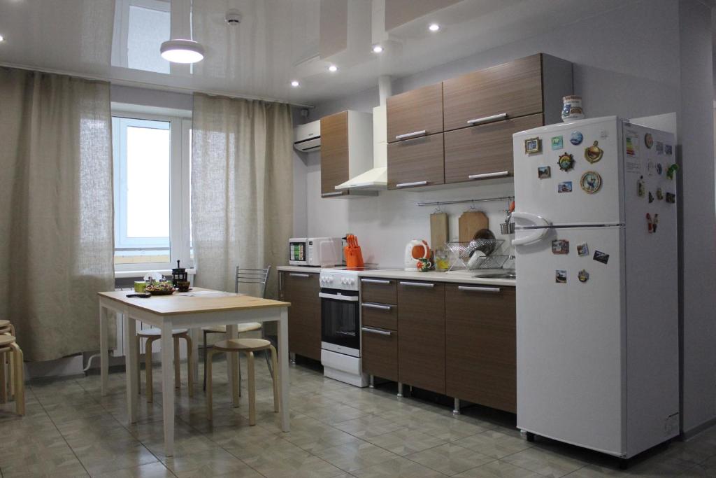 a kitchen with a white refrigerator and a table at Apartment on Chernyakhovskogo 5V in Vladivostok