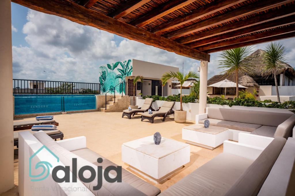 un patio con muebles blancos y una piscina en Hotel Zendero Tulum en Tulum