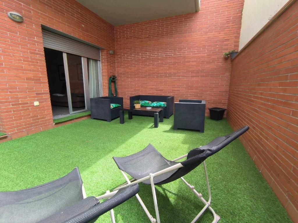 マタローにあるMazi Apartments Terraceのレンガの壁、芝生と椅子付きのパティオ