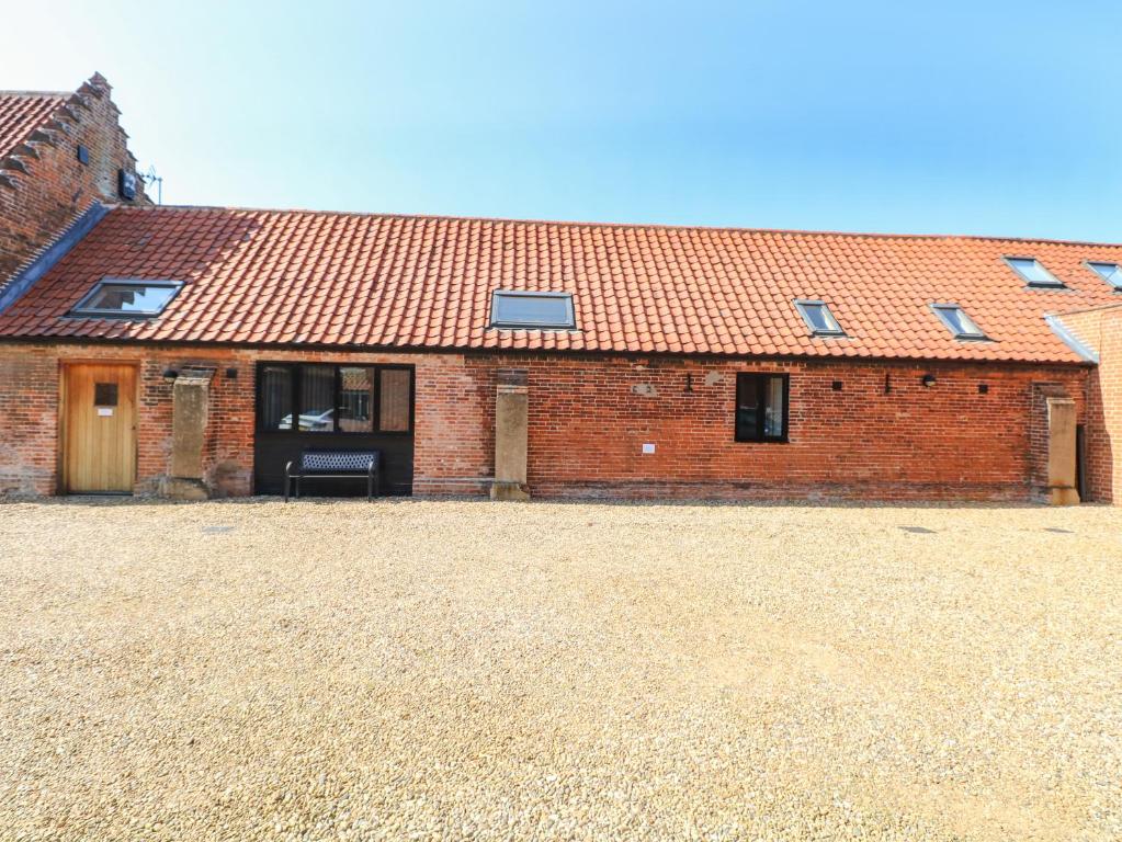 a brick house with a red roof with a large yard at The Long Barn in Attlebridge