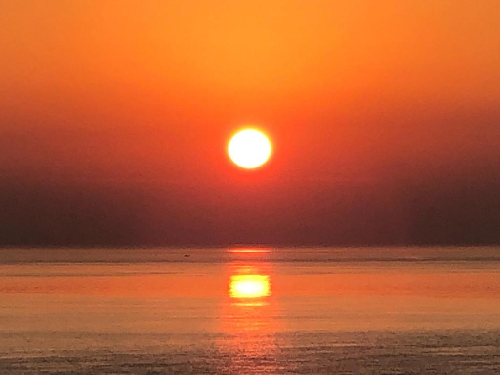 un coucher de soleil sur l'eau avec le soleil dans le ciel dans l'établissement Cliff top terrace - Vacation STAY 76503v, à Kuranomoto