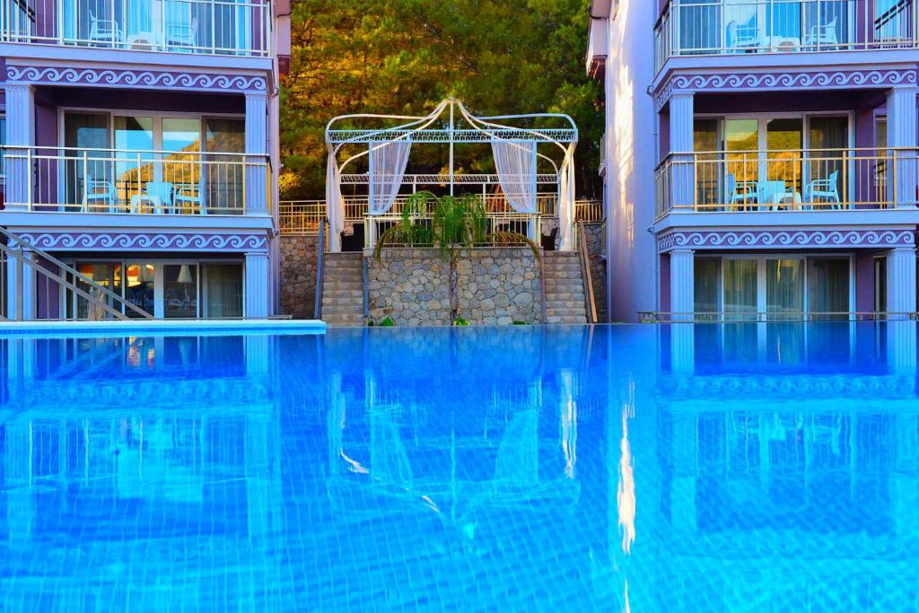 a large blue swimming pool in front of a building at Nokta Paspatur Suit Apart, Fethiye, Ölüdeniz in Fethiye