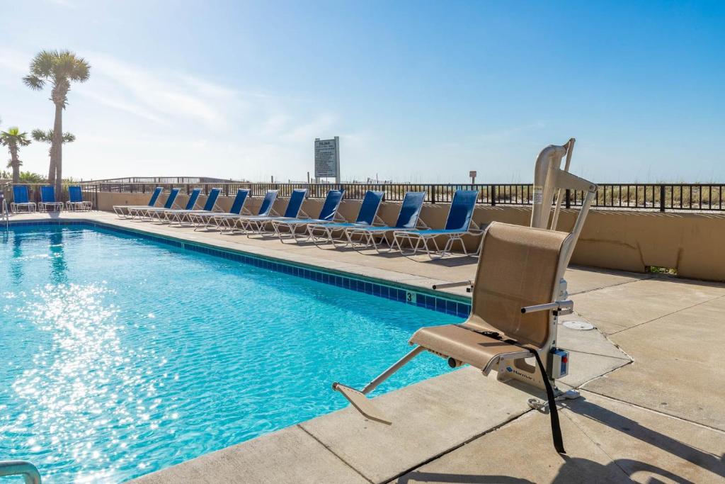 a swimming pool with chairs next to a swimming pool at Phoenix All Suites West Hotel in Gulf Shores