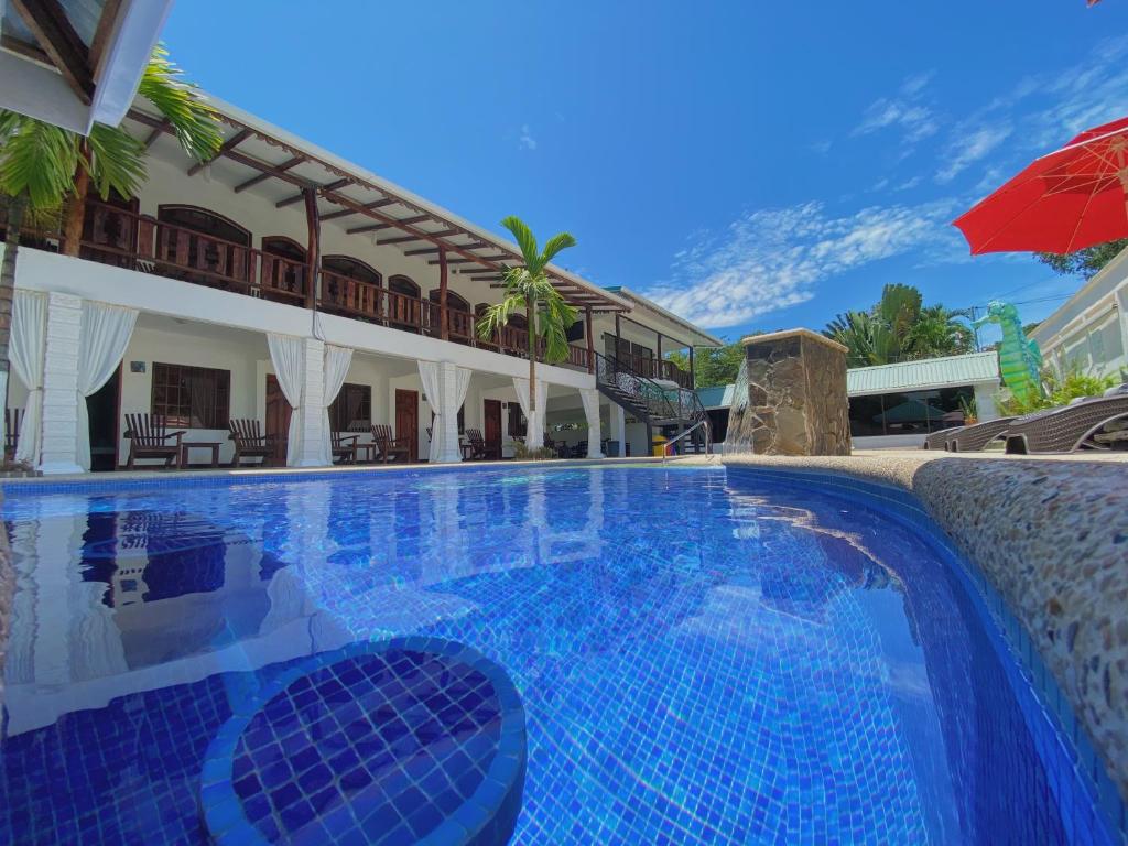 einen Pool vor einem Haus mit Sonnenschirm in der Unterkunft Ocean View Lodge in Cahuita