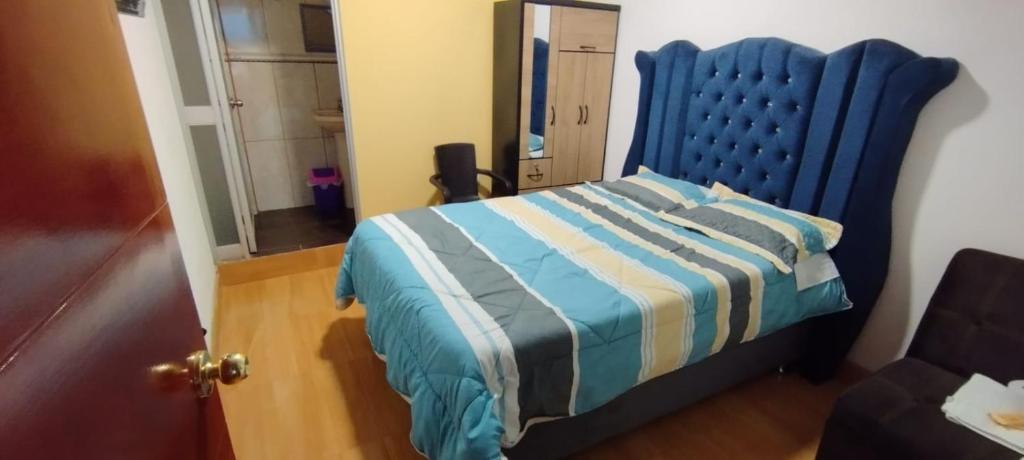 a bed with a blue headboard in a room at Hostel Las Gardenias Ayacucho in Ayacucho