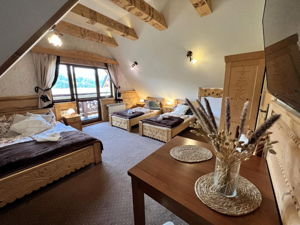 a room with two beds and a table with a vase of flowers at Willa Siumno in Białka Tatrzanska