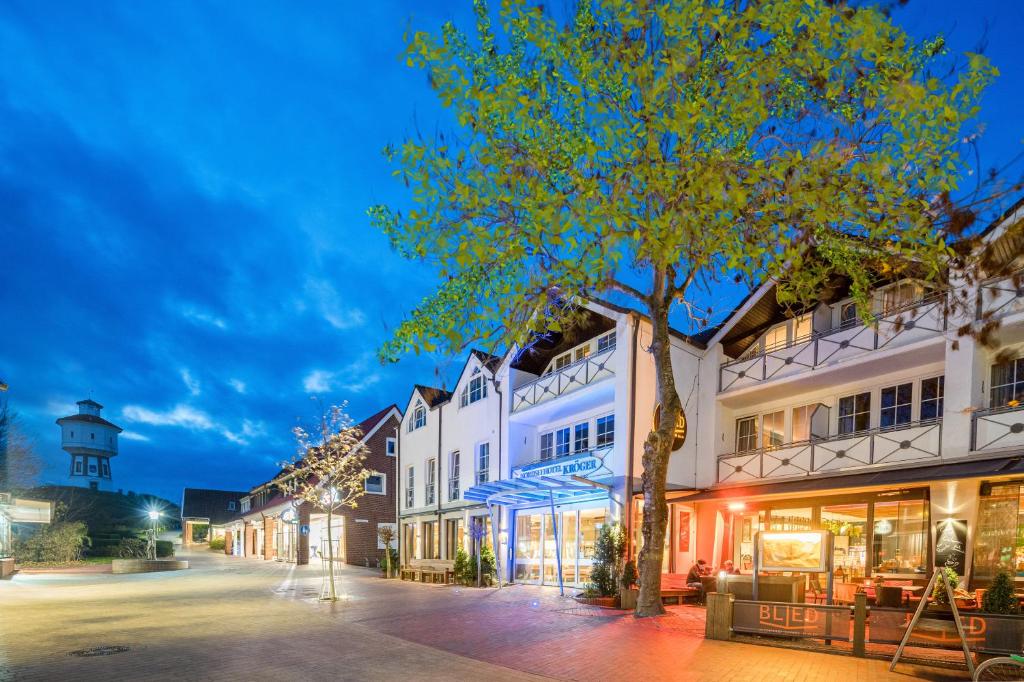 eine Stadtstraße mit Gebäuden und einem Leuchtturm in der Unterkunft Nordseehotel Kröger in Langeoog