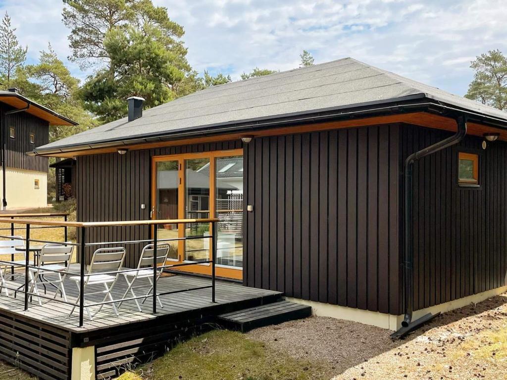 una casa negra con sillas en una terraza en Holiday home ÅHUS, en Åhus