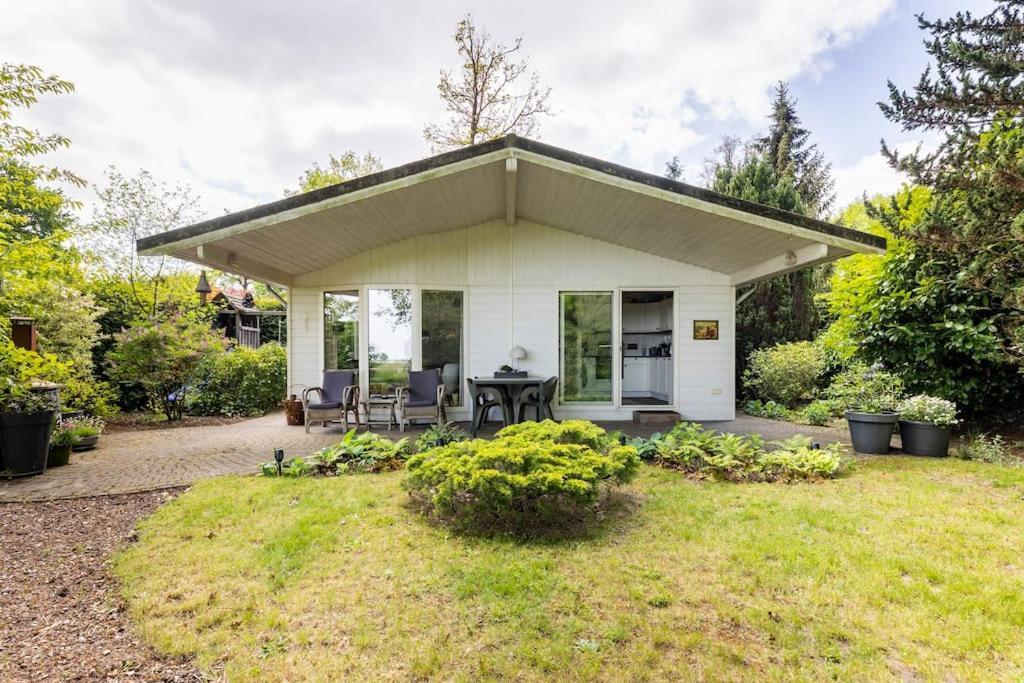 a white cottage with a table and chairs in a yard at NOFLIK, een gezellig chalet met een fraaie en rustige ligging in Stegeren