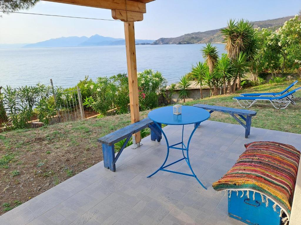 une table et un banc bleus sur une terrasse donnant sur l'eau dans l'établissement Beach Studio Kotrona, à Achladi