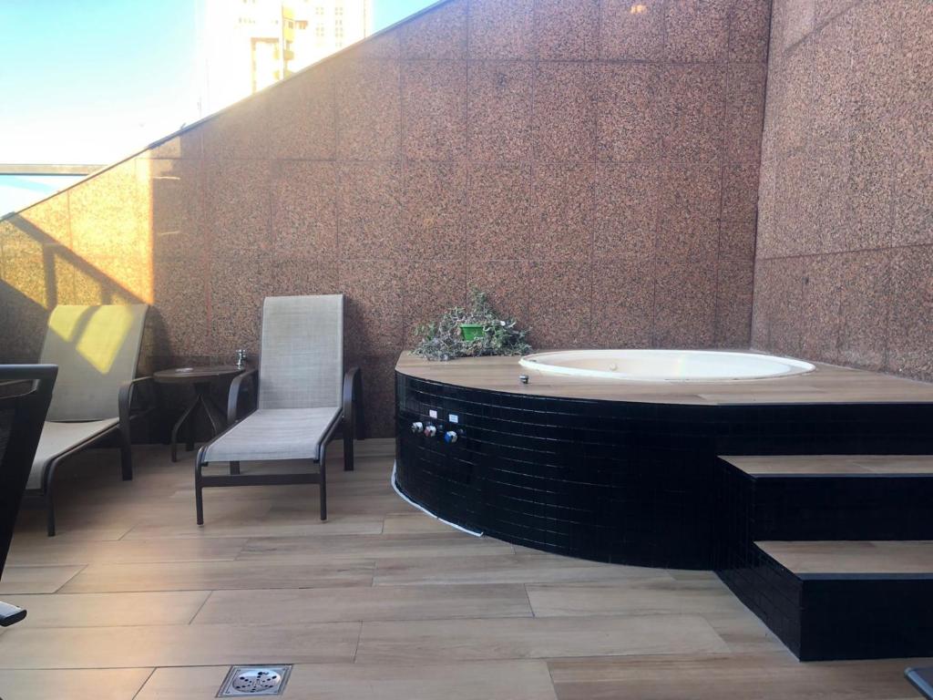 un ampio bagno con vasca e sedia di Condomínio Tower Cobertura 1503 a Belo Horizonte