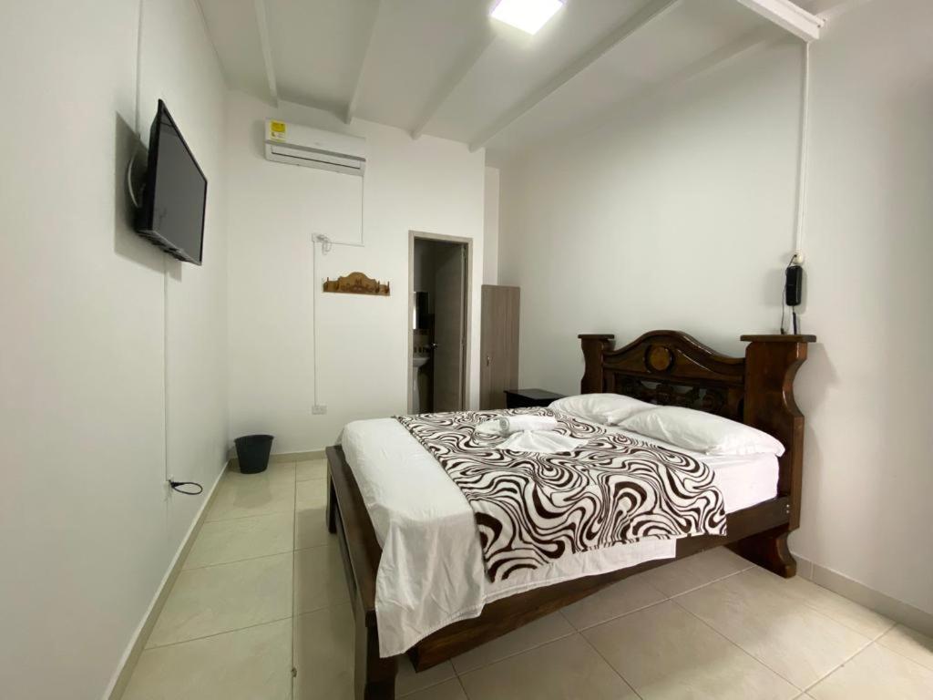 ein Schlafzimmer mit einem Bett und einem TV an der Wand in der Unterkunft Hotel Monaco in Tuluá